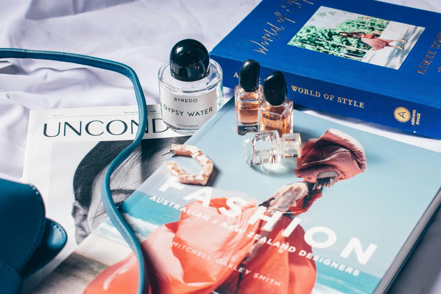 A stylish arrangement of fashion books, perfume bottles, and jewelry showcasing the intersection of media, style, and luxury in the fashion industry.