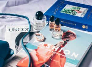 A stylish arrangement of fashion books, perfume bottles, and jewelry showcasing the intersection of media, style, and luxury in the fashion industry.